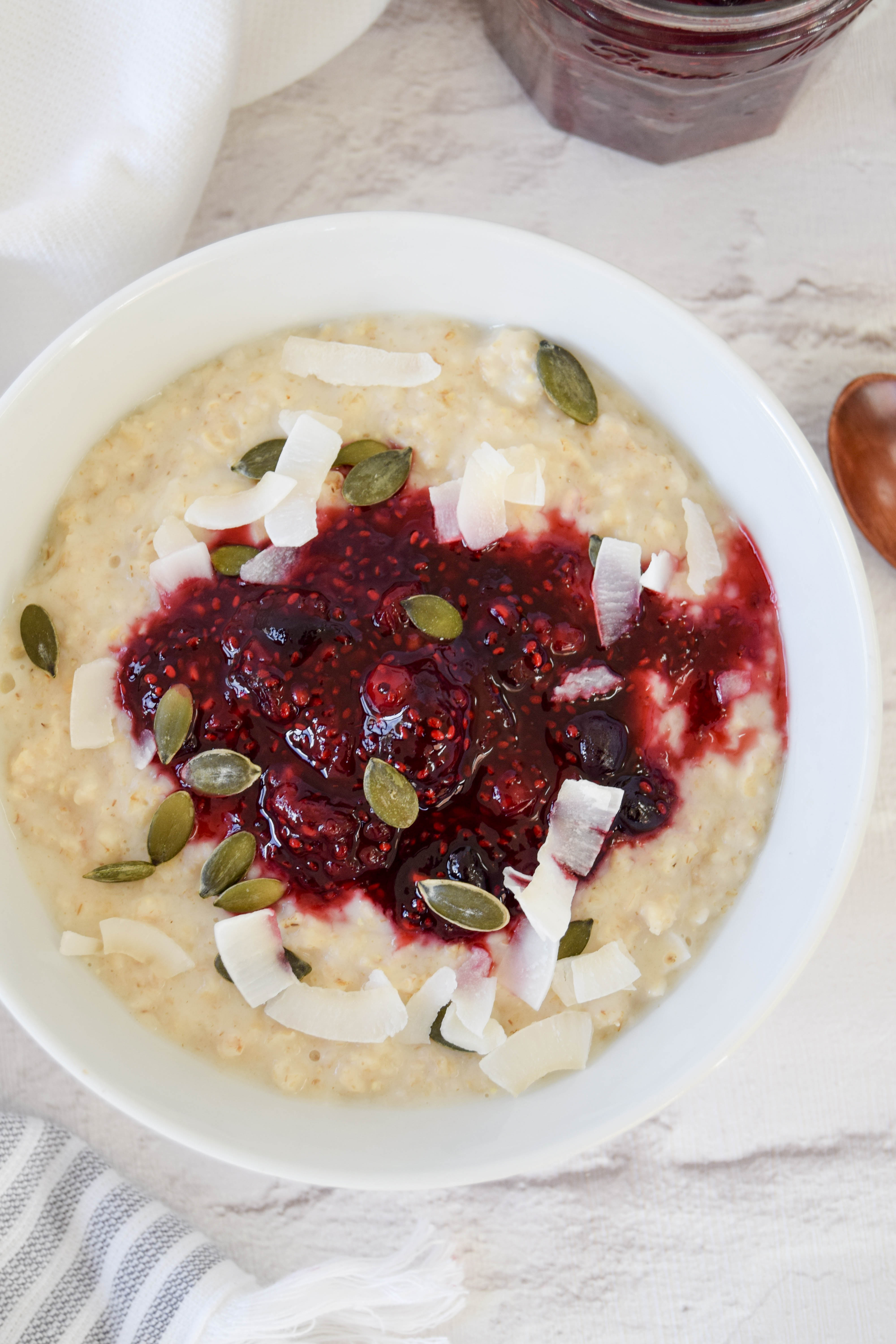 A delicious creamy coconut porridge breakfast bowl topped with a juicy homemade chia berry compote.