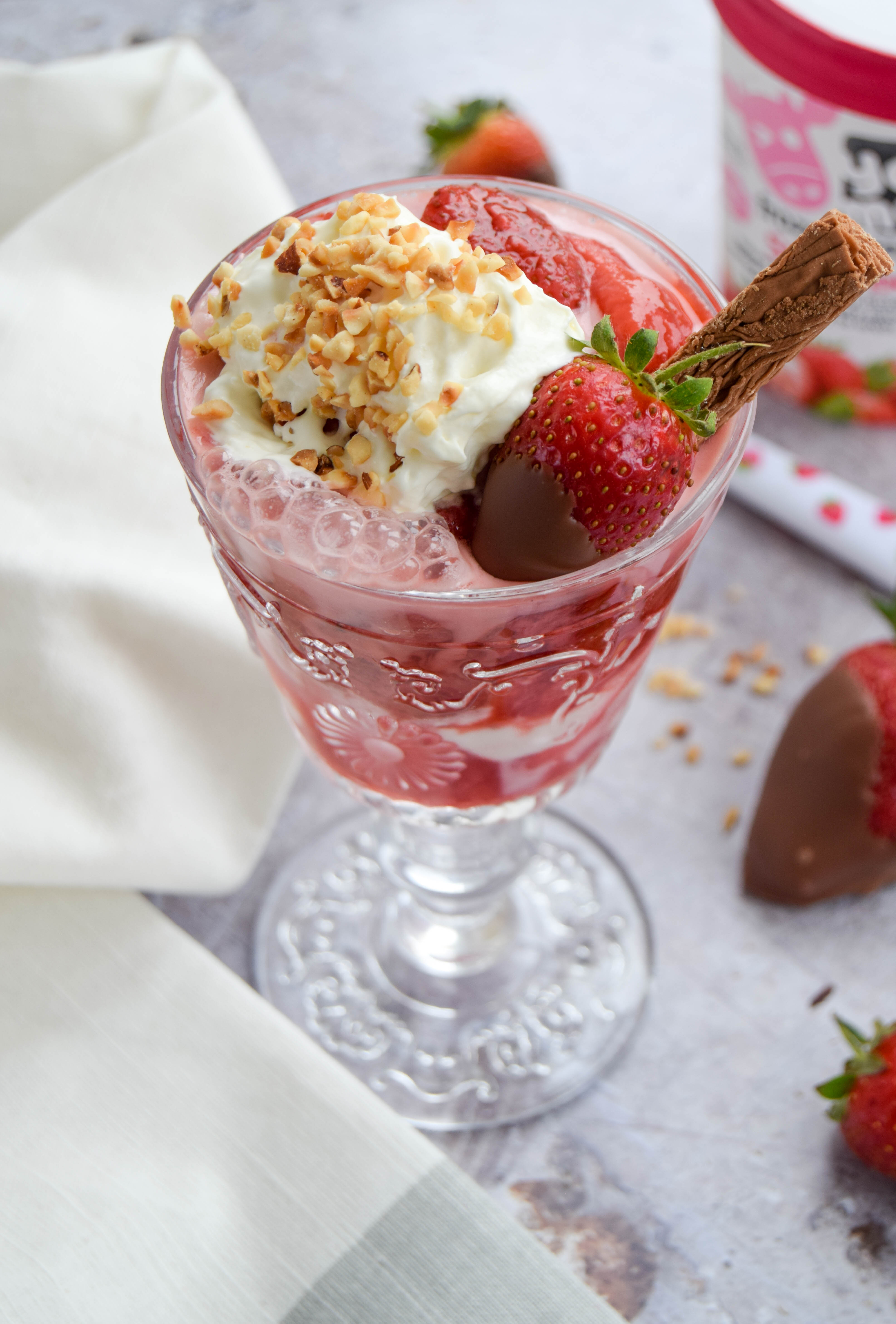 A fruity and vibrant strawberry sundae dessert topped with chocolate covered strawberries - perfect to serve at BBQ's and all your upcoming summer parties. 